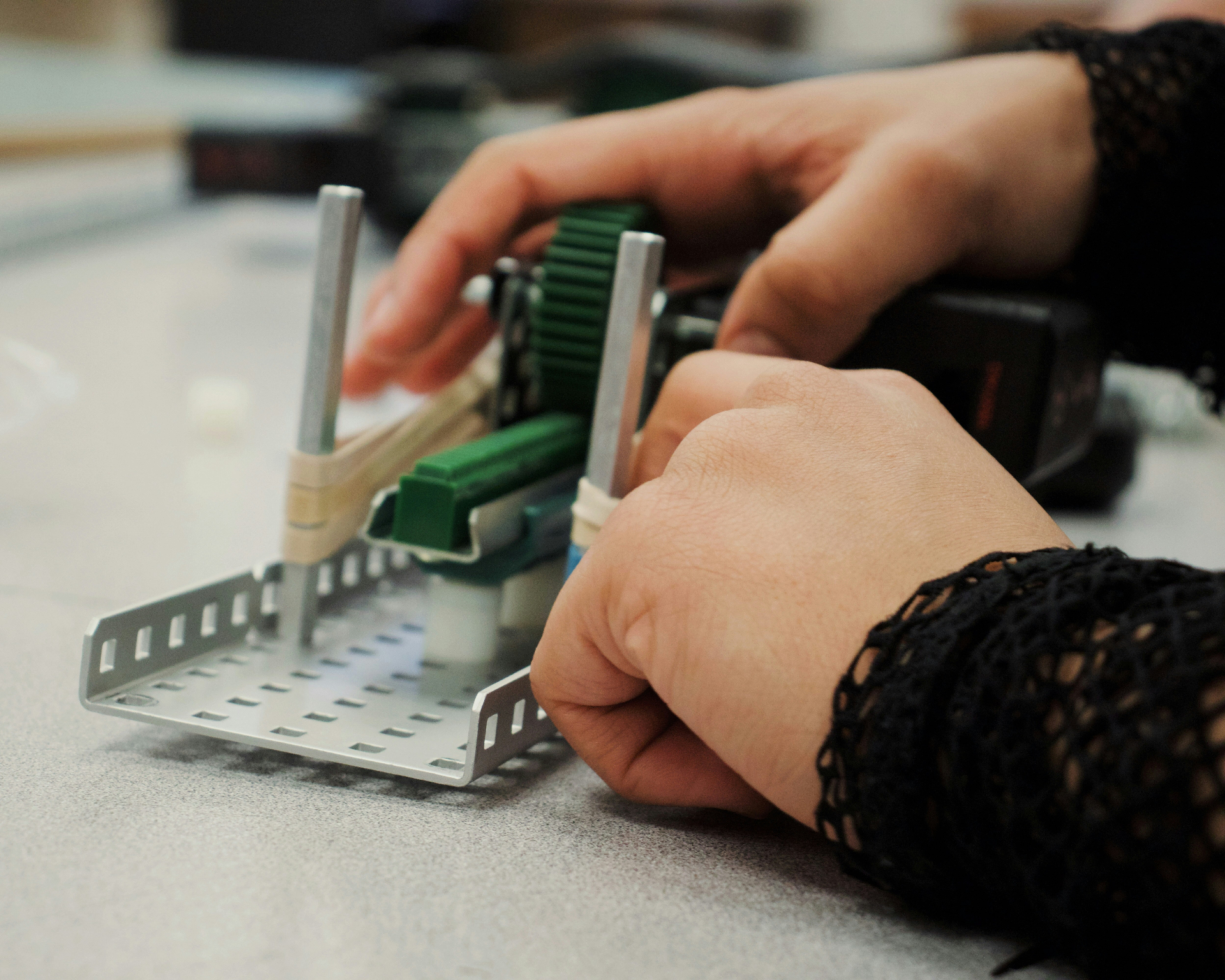 Close-up of hands assembling a mechanical engineering prototype.