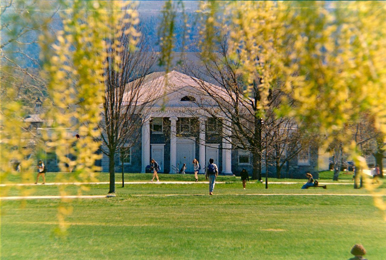 Students walking across a campus lawn.