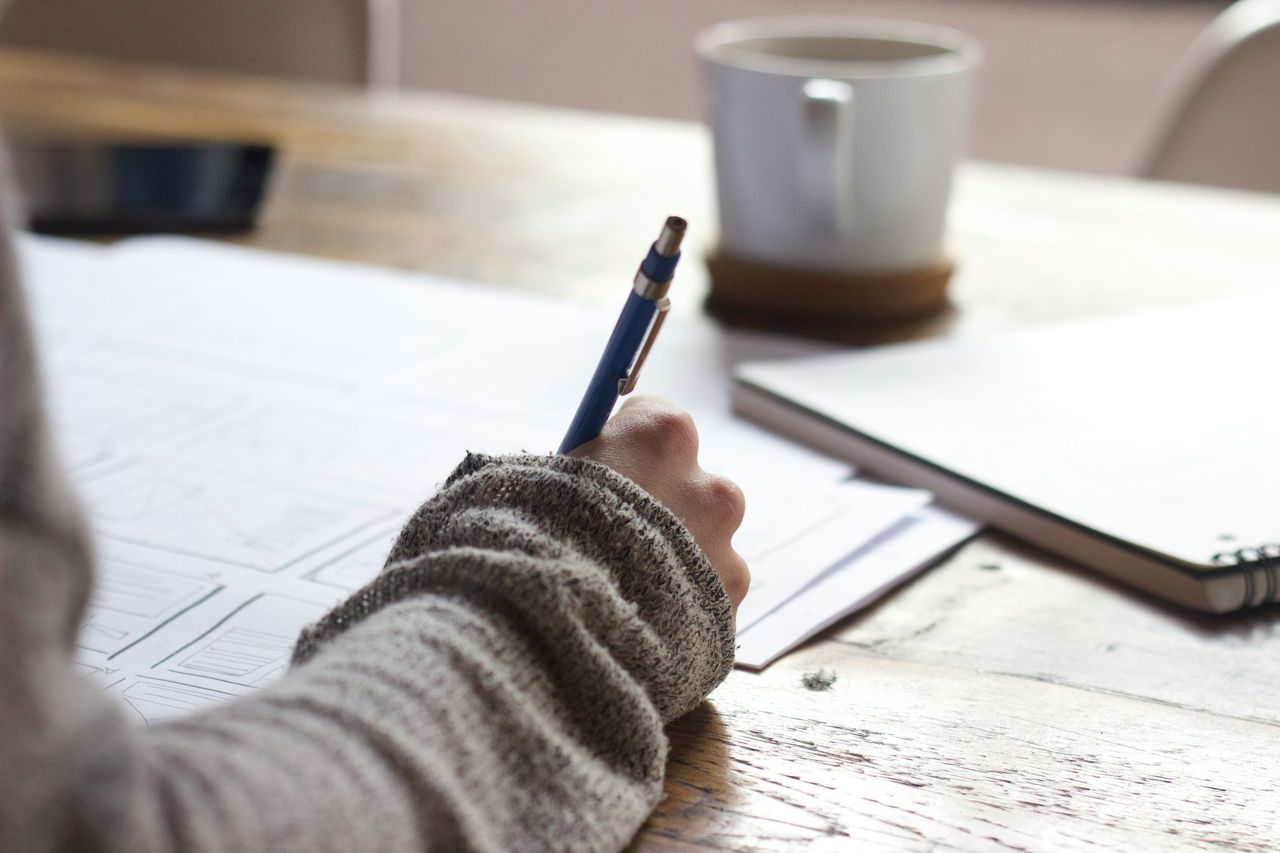 Person writing notes at a desk.